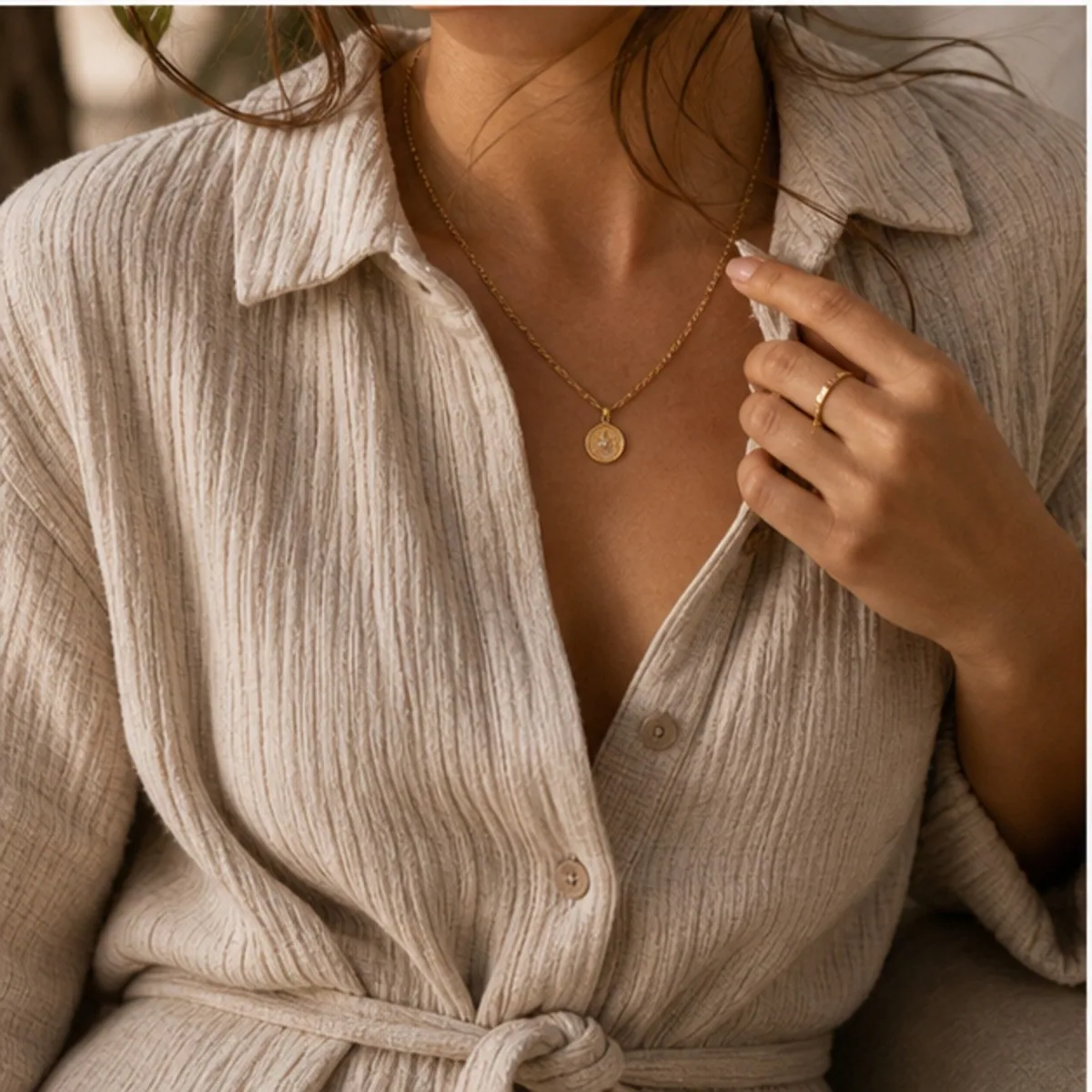 Close-up of a textured linen shirt worn open with a gold pendant necklace.